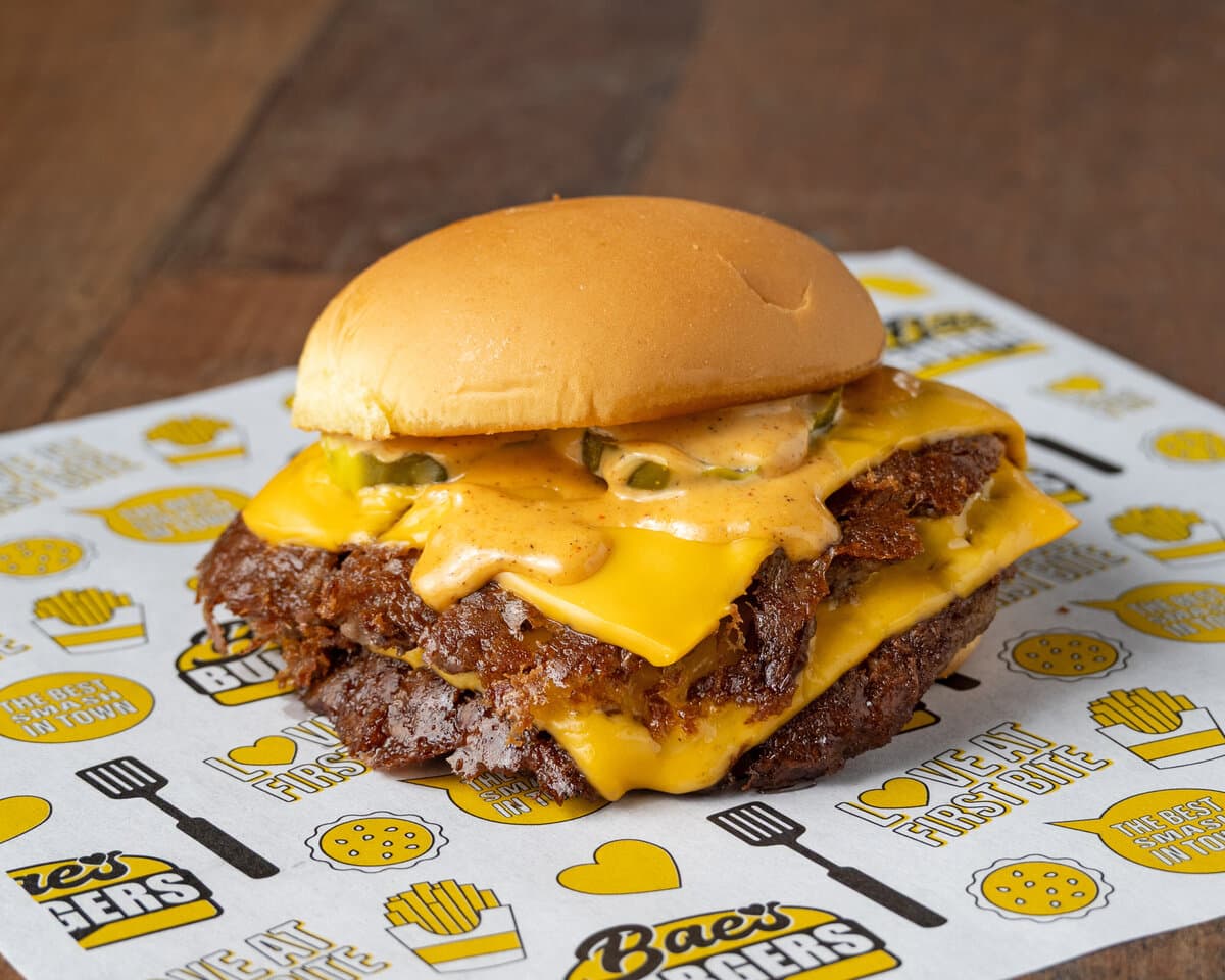 Double smash burger with cheese and pickles on paper