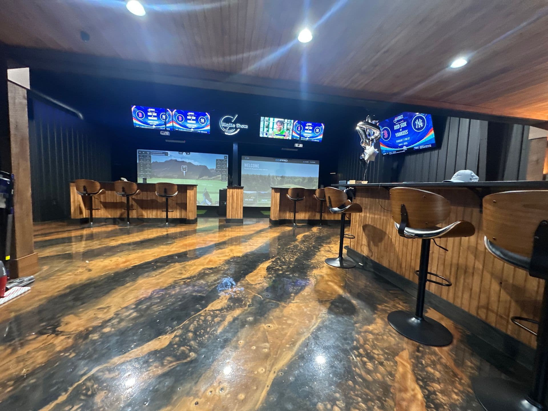 Interior view with golf simulators, bar stools, and screens