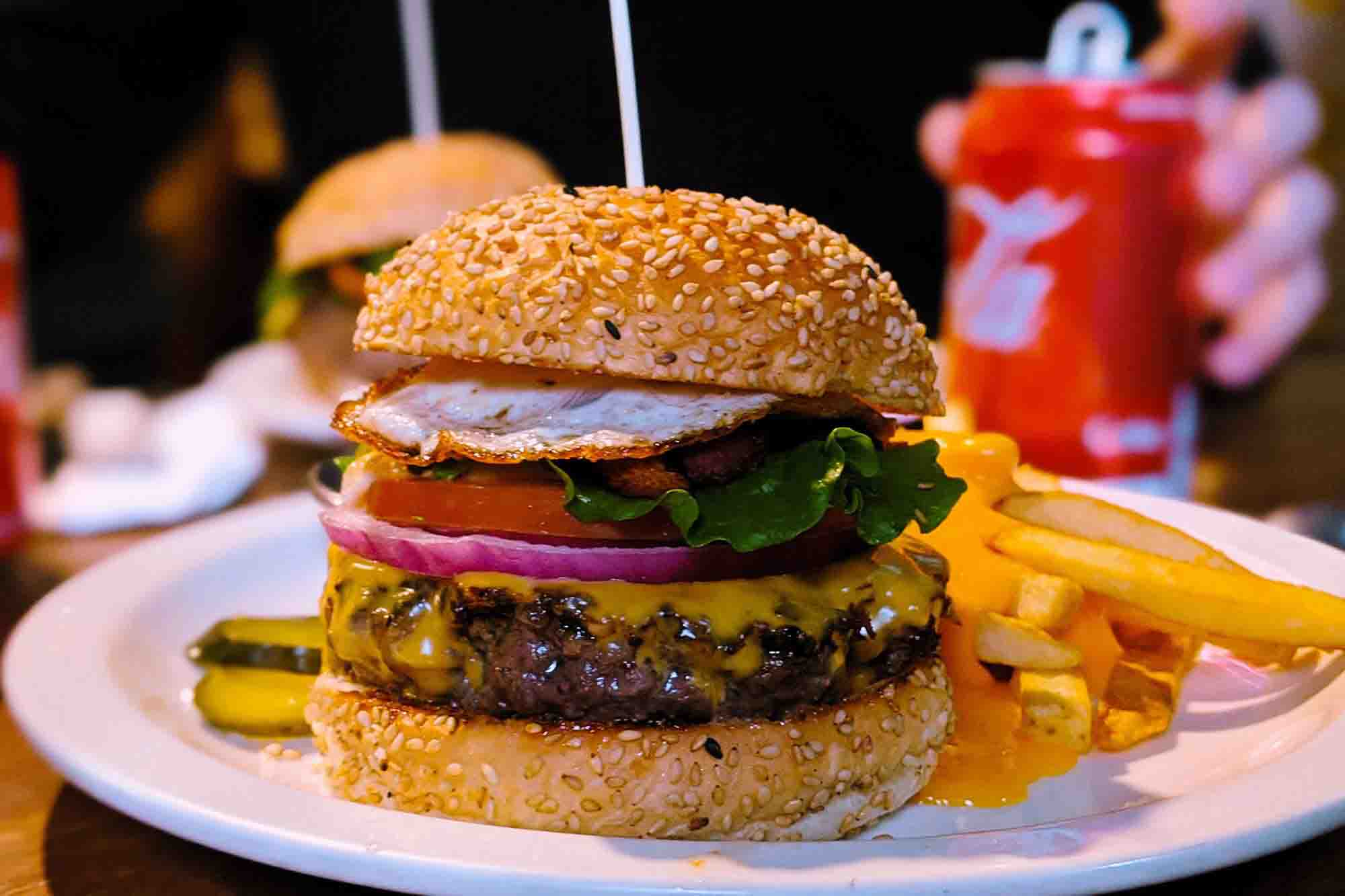 Cheeseburger with fried egg, fries, and pickle on plate