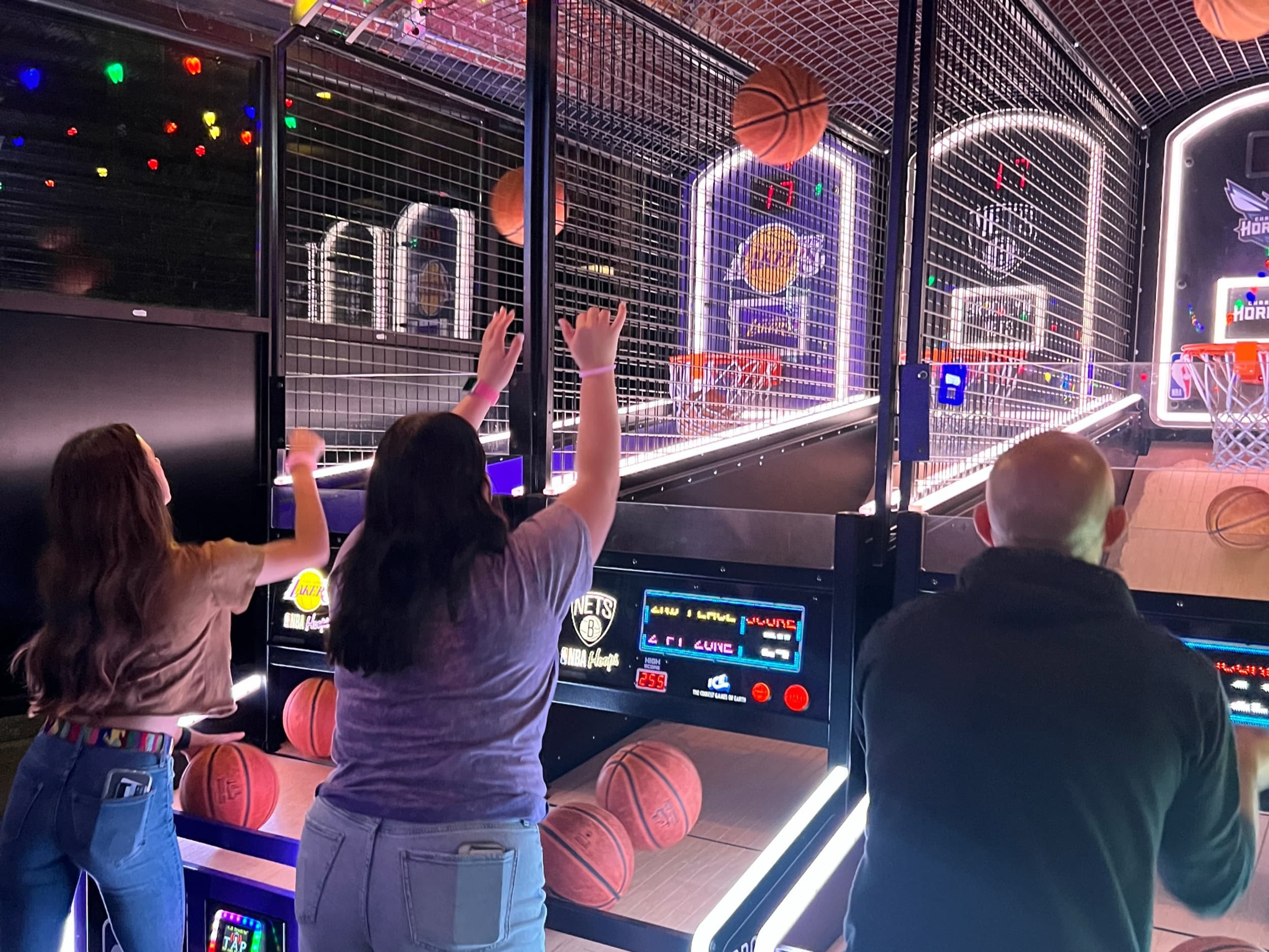 People playing arcade basketball hoops game inside venue