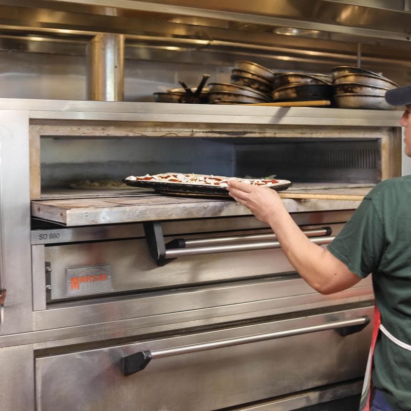 Pizza being placed into a commercial oven