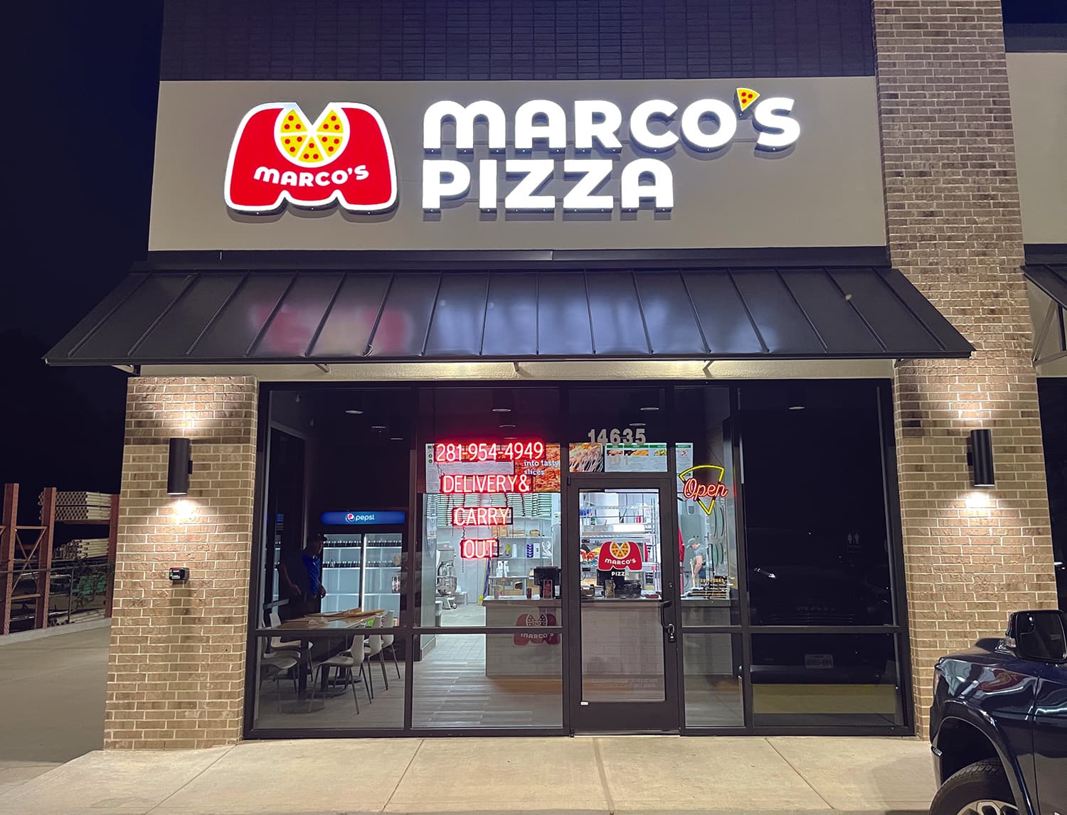 Marco's Pizza storefront exterior with lit signage at night