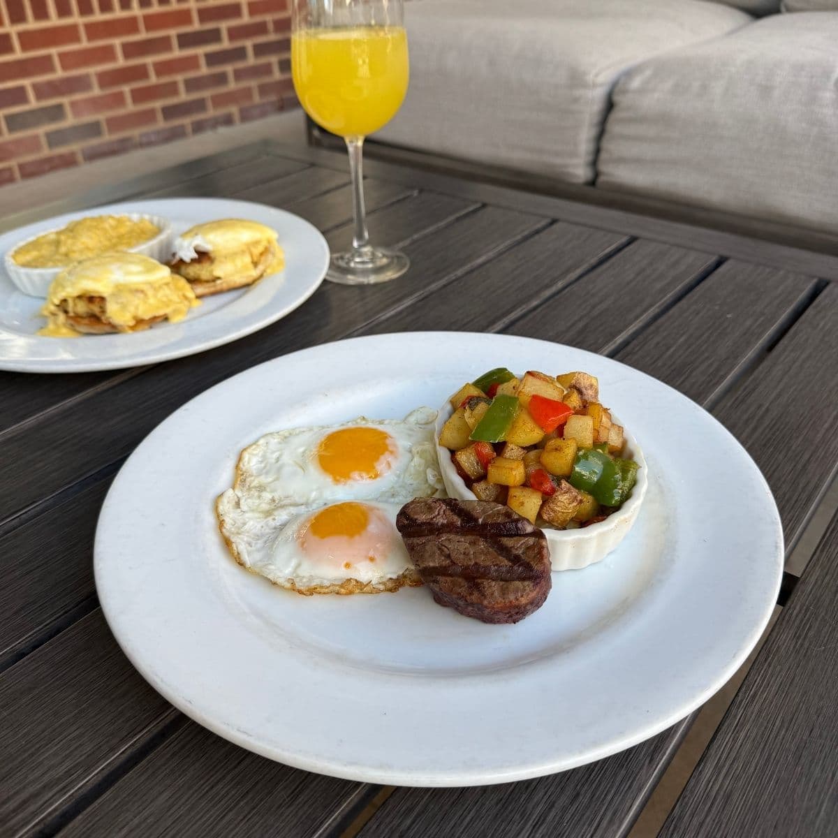Breakfast plate with eggs, steak, potatoes and mimosa