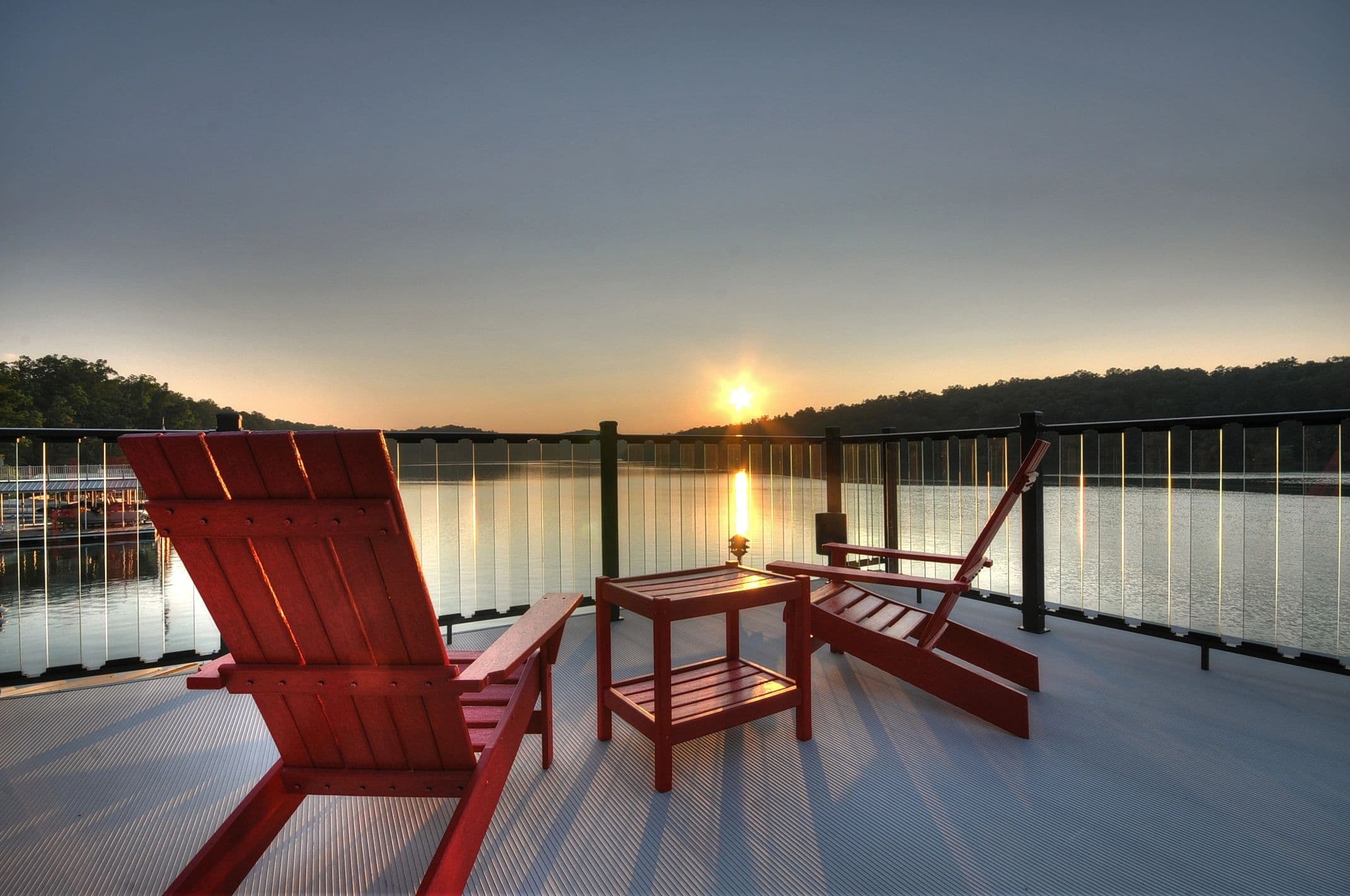 Waterfront deck with red chairs at sunset