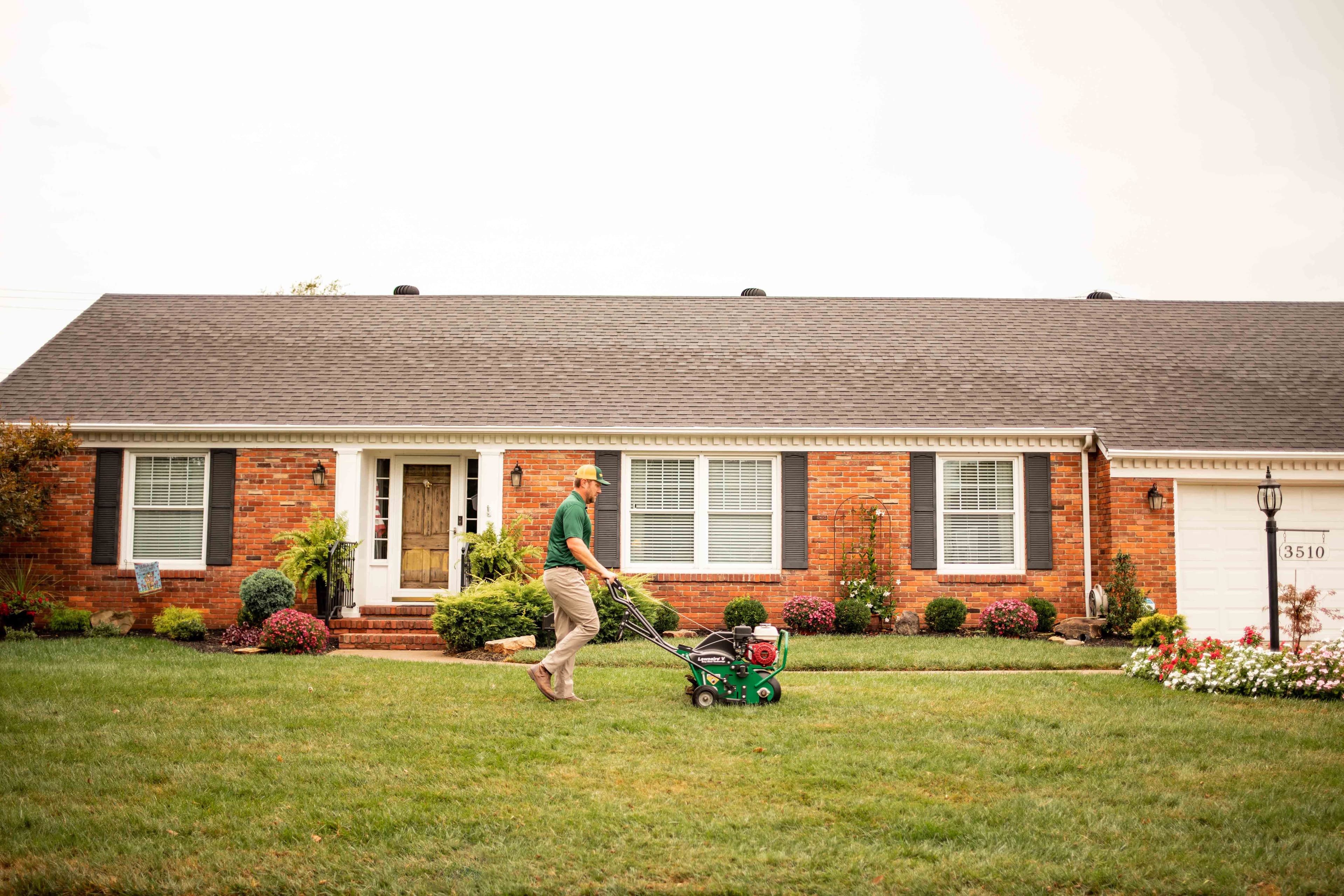 Man mowing residential lawn with equipment