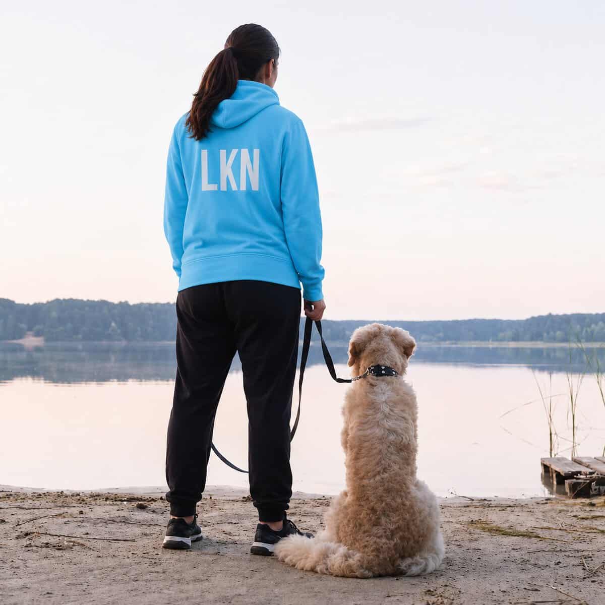 Pet sitter walking dog by lakeside