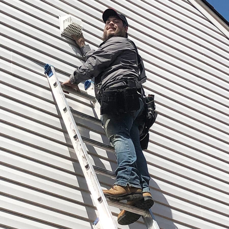 Worker on ladder installing dryer vent