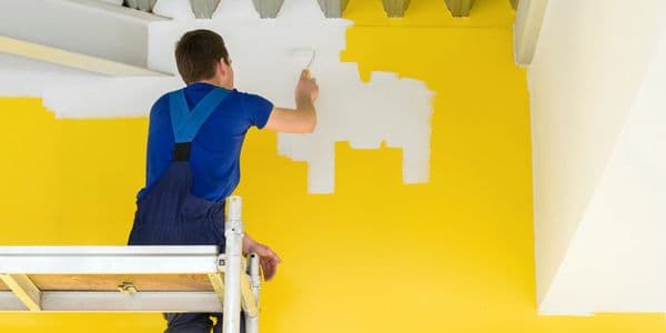 Worker painting interior wall yellow