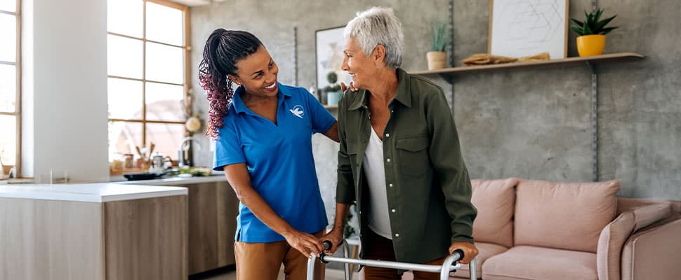 Caregiver assisting elderly woman with walker