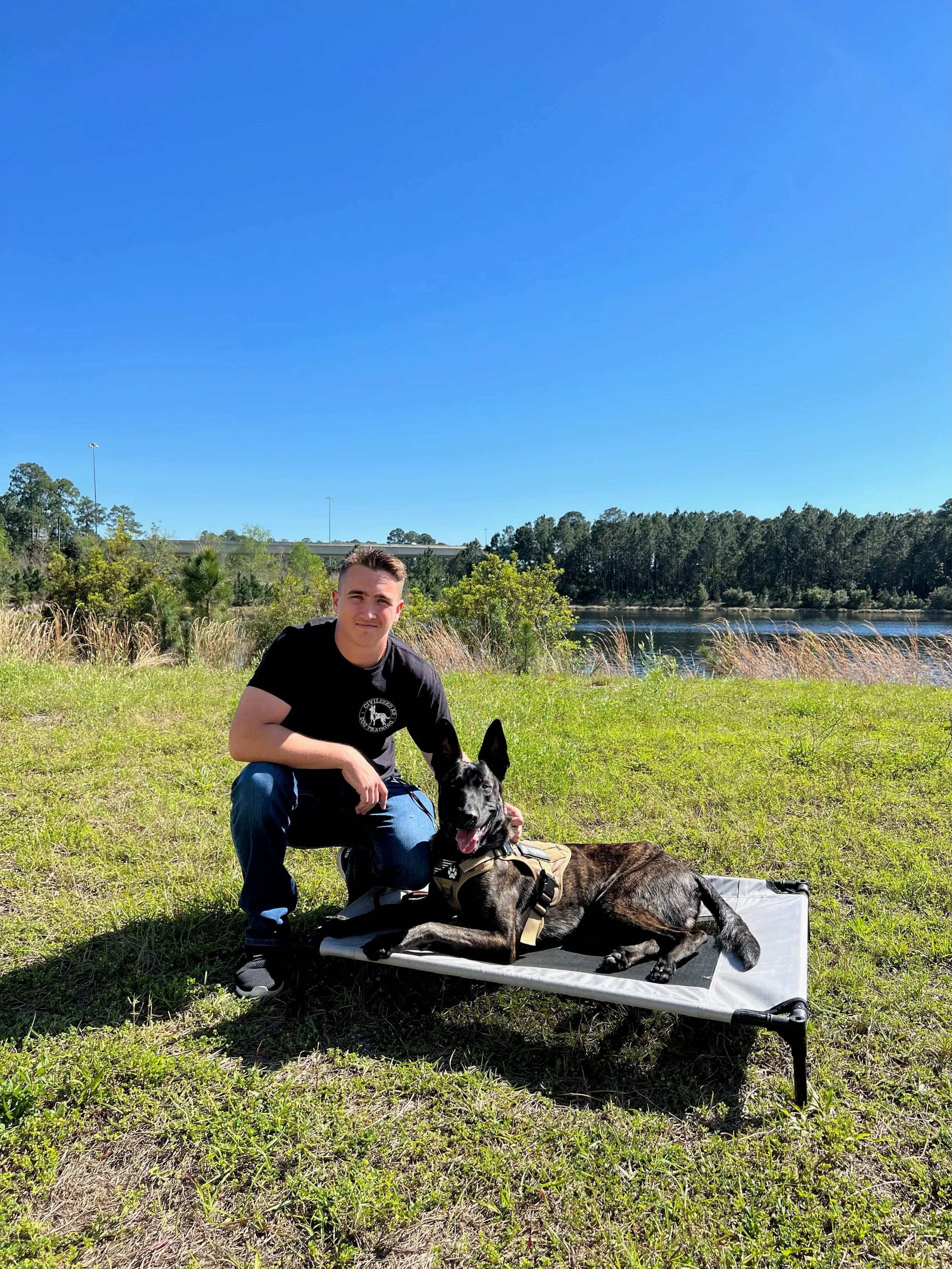 Man with German Shepherd dog by water