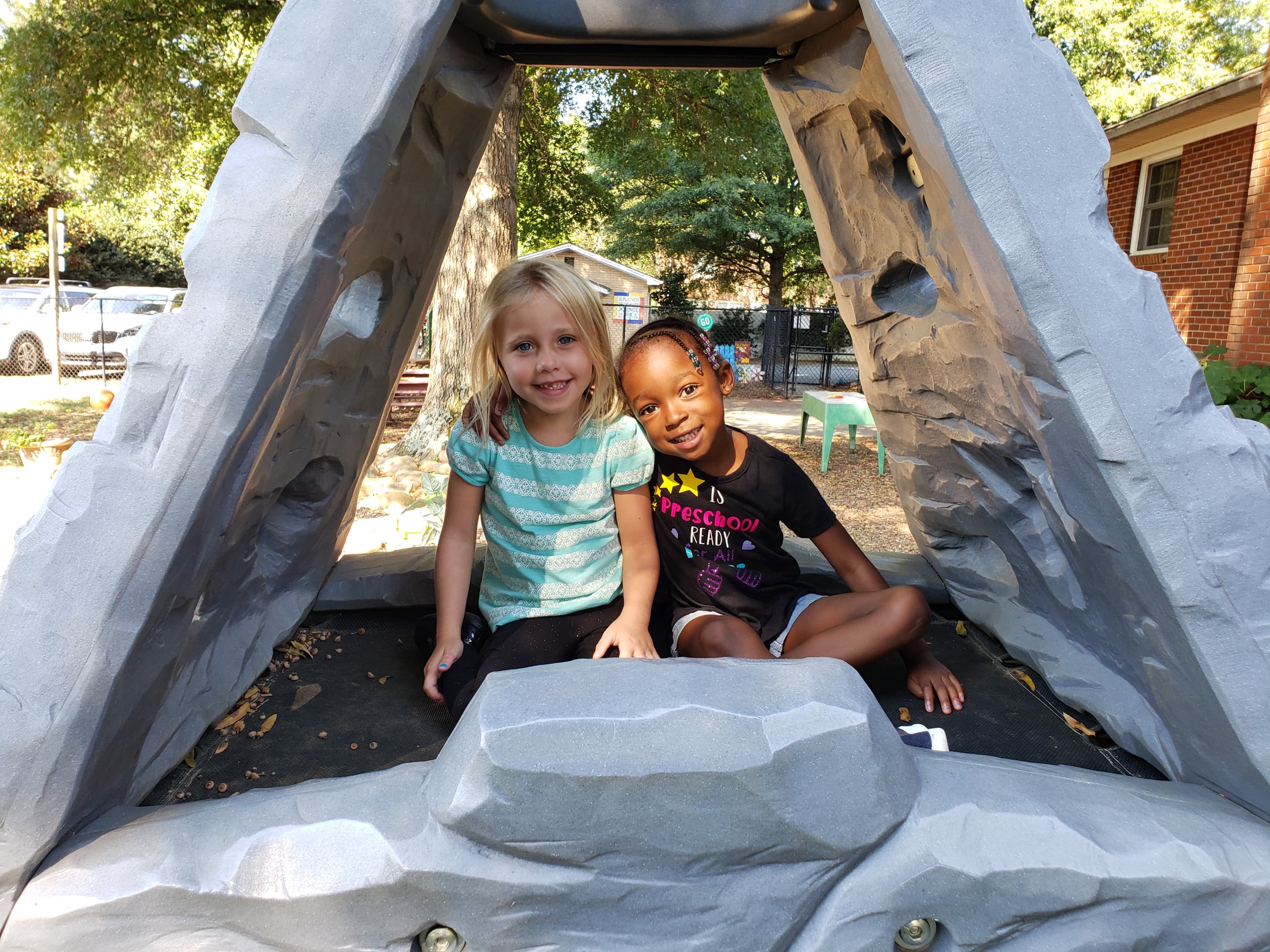 Two children playing in playground tunnel structure