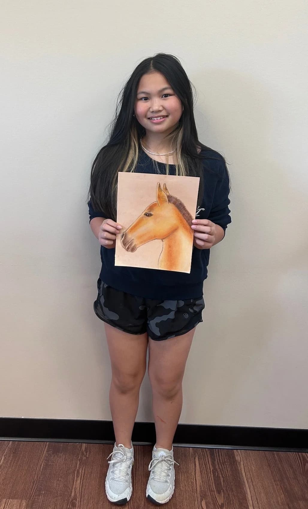 Student displaying horse drawing artwork