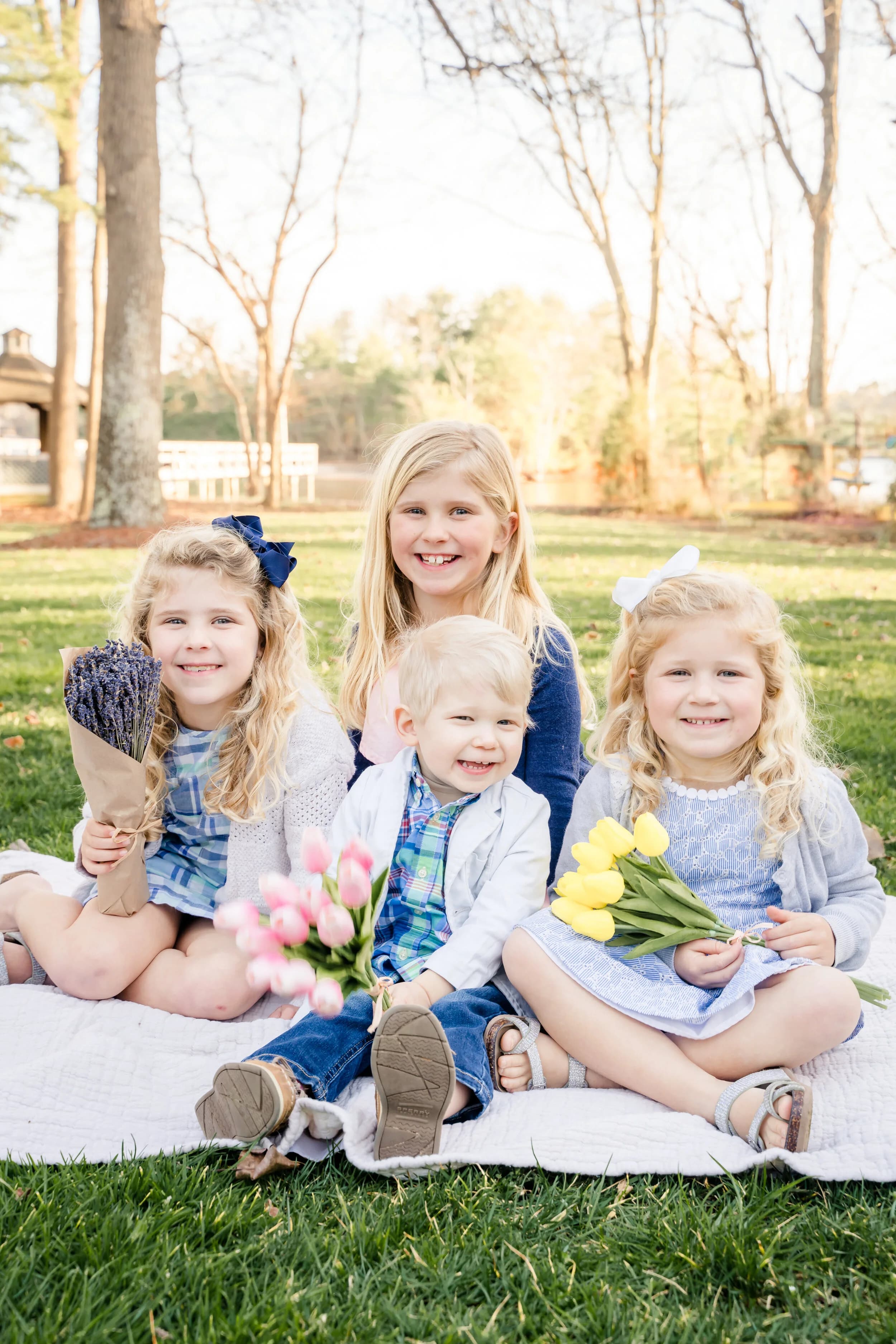 Four young children with flowers outdoors