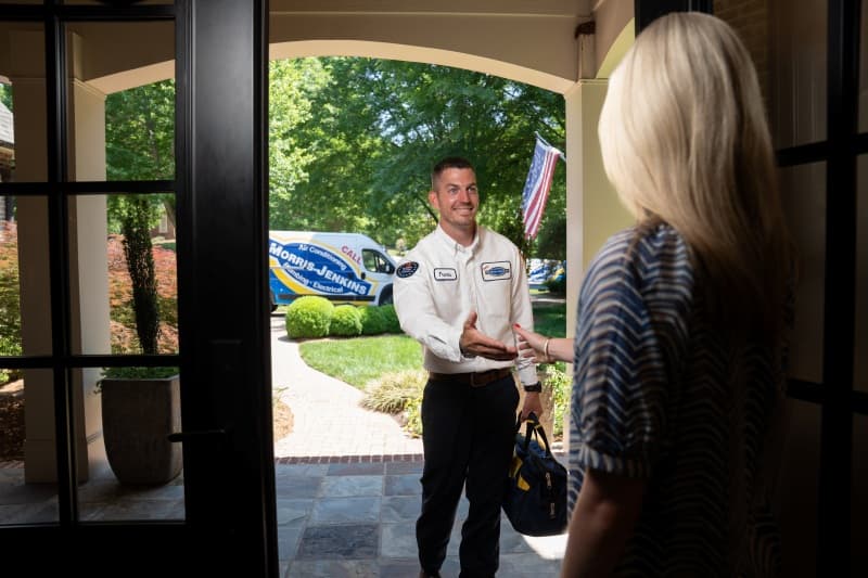 Technician at customer doorway with service van