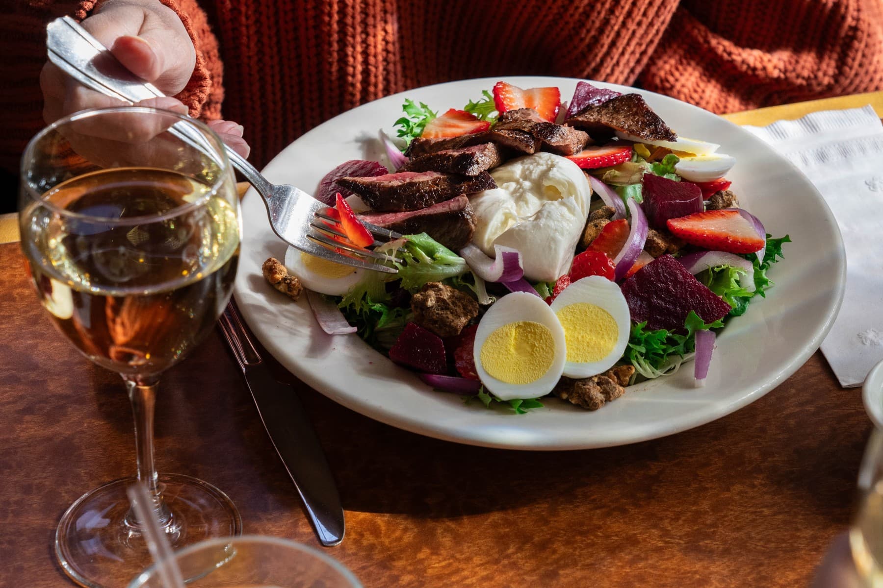 Steak salad with egg, burrata, strawberries on plate