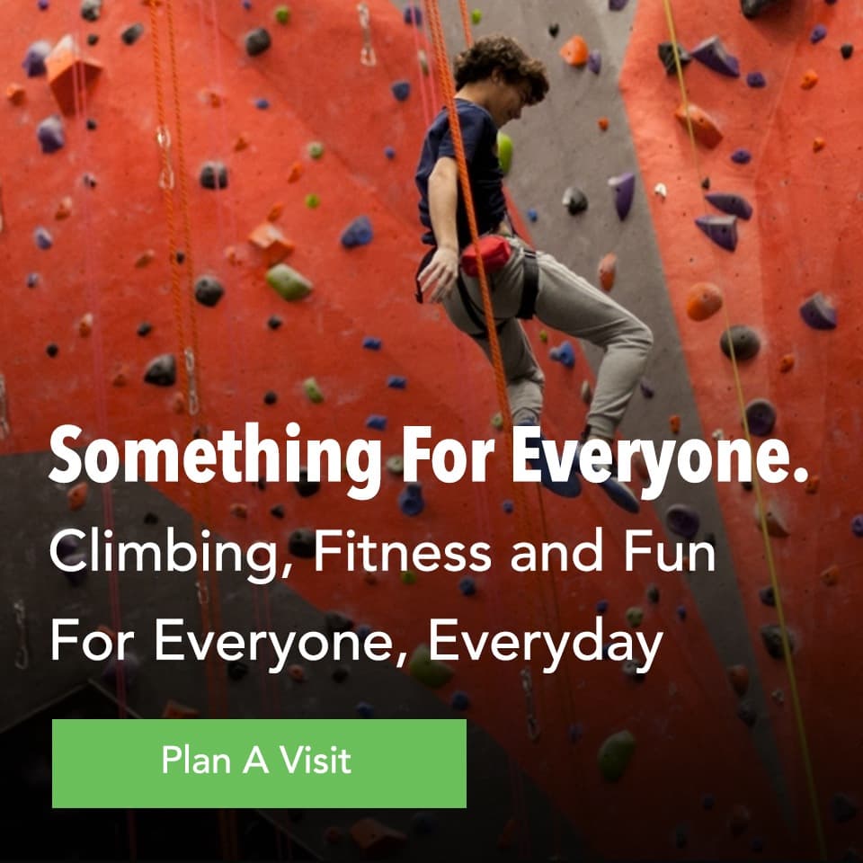 Climber ascending indoor rock wall with colorful holds