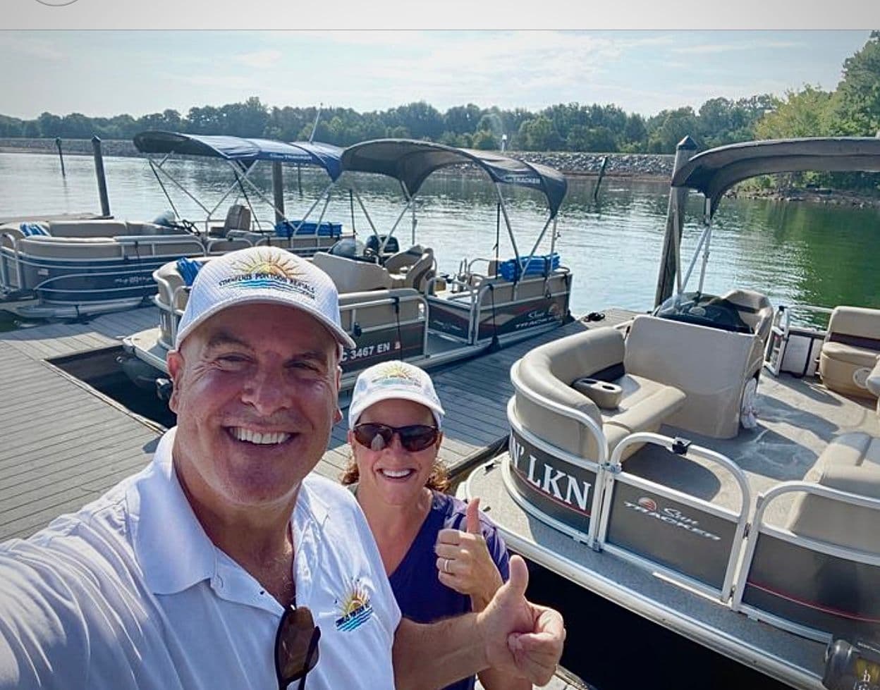 Man and woman with pontoon rental boats at dock