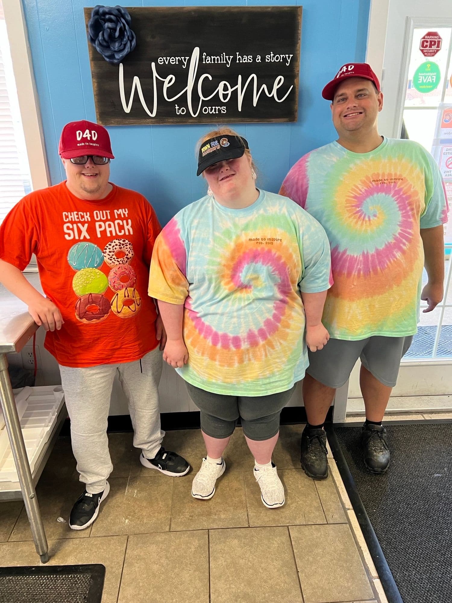 Three people posing inside the shop by welcome sign