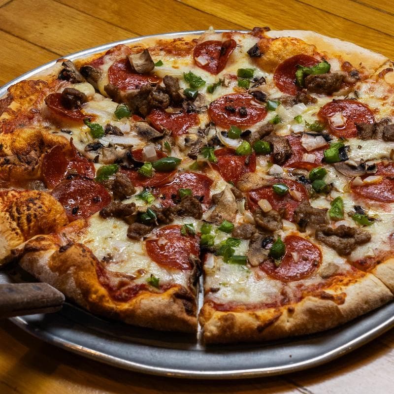 Loaded pepperoni sausage pizza on metal tray