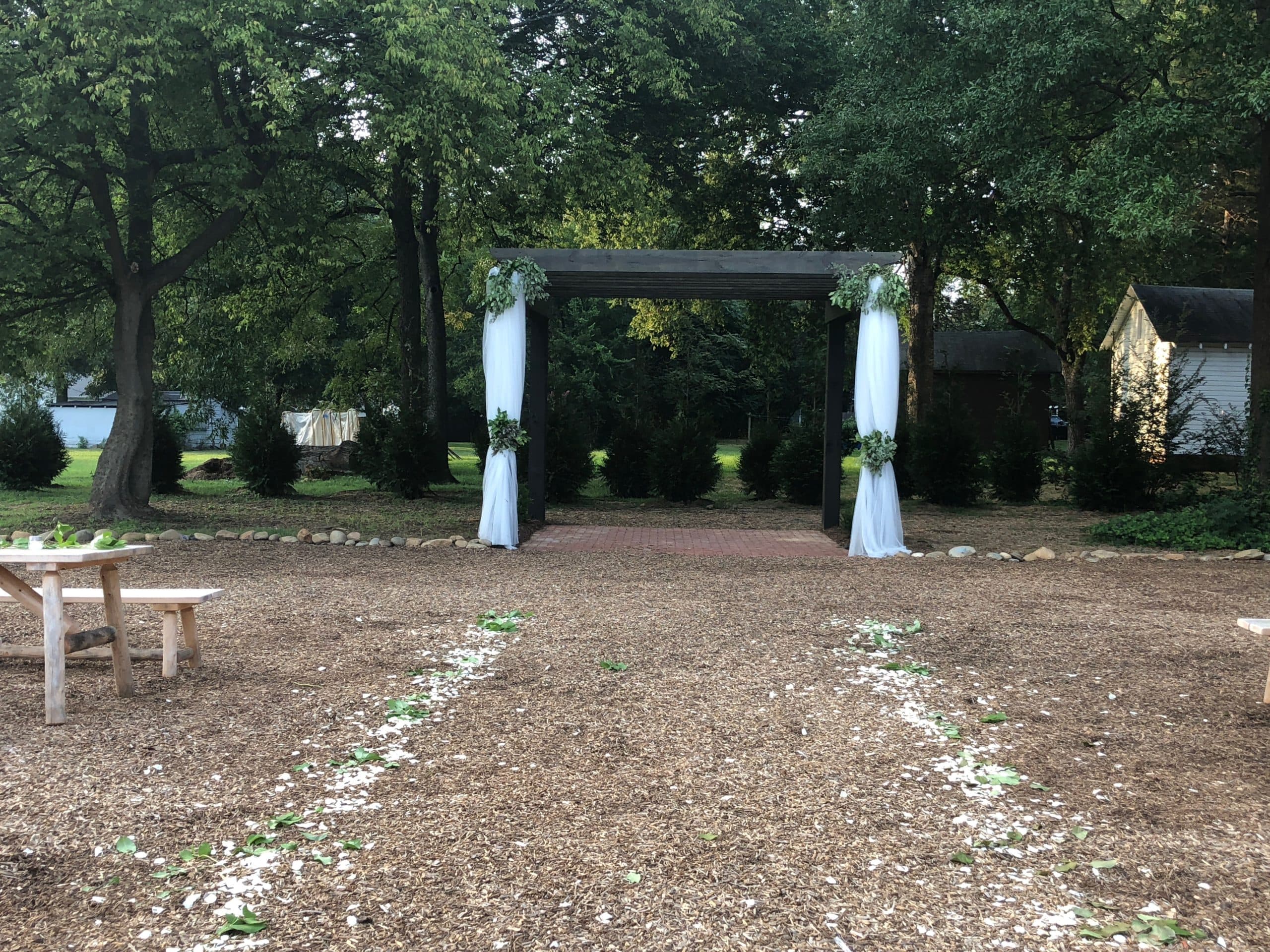 Outdoor wedding pergola with draped fabric and greenery