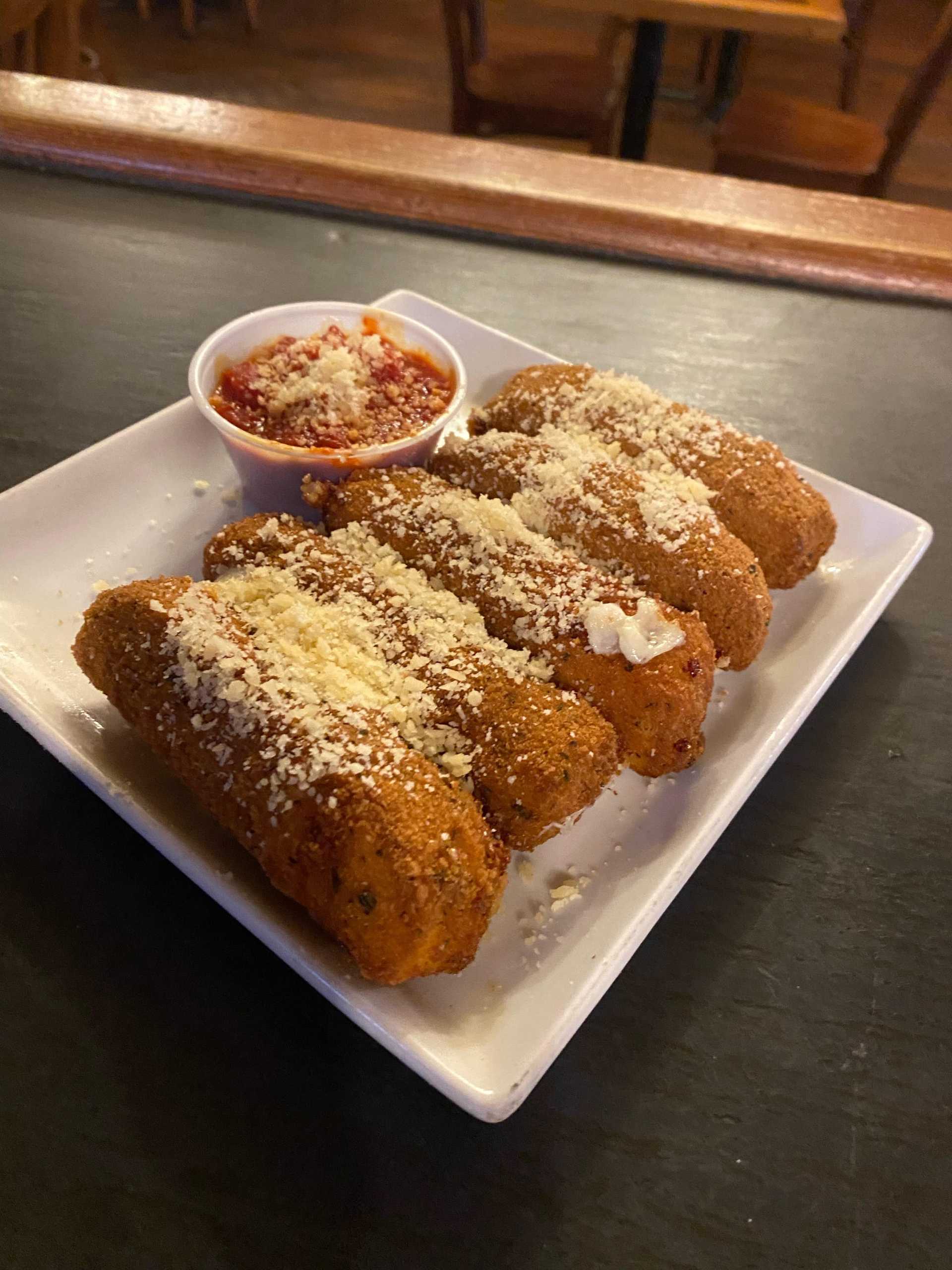 Fried mozzarella sticks with marinara on plate