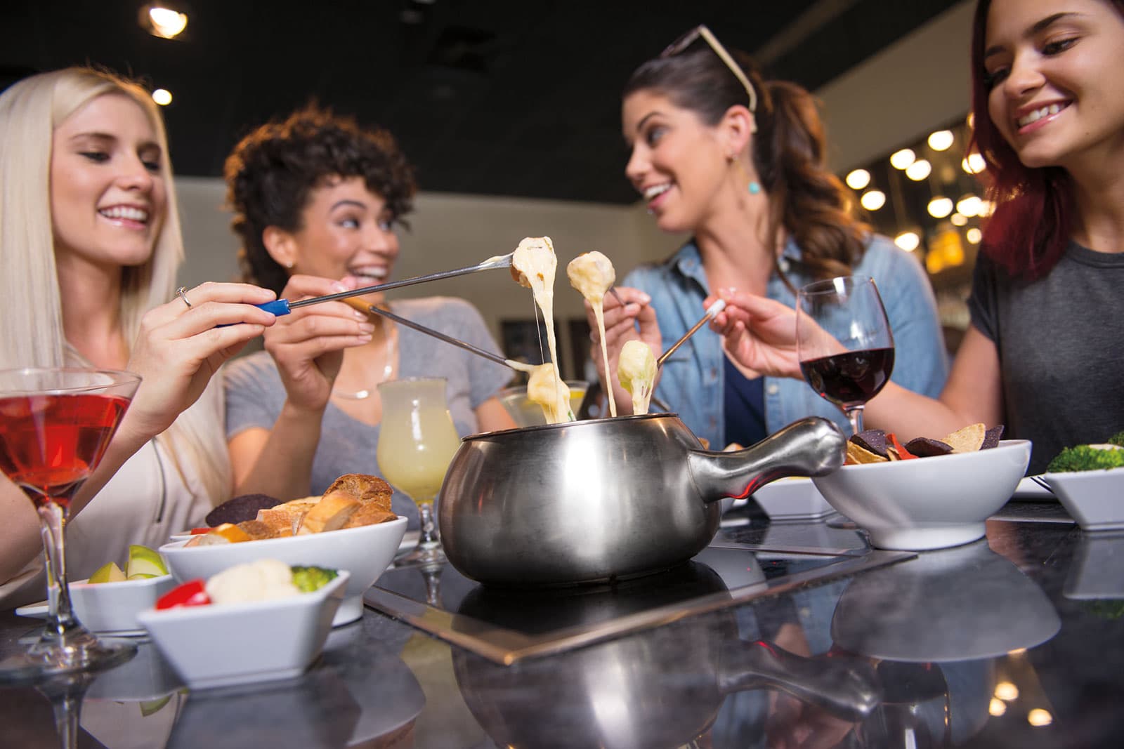 Group of women enjoying cheese fondue at restaurant