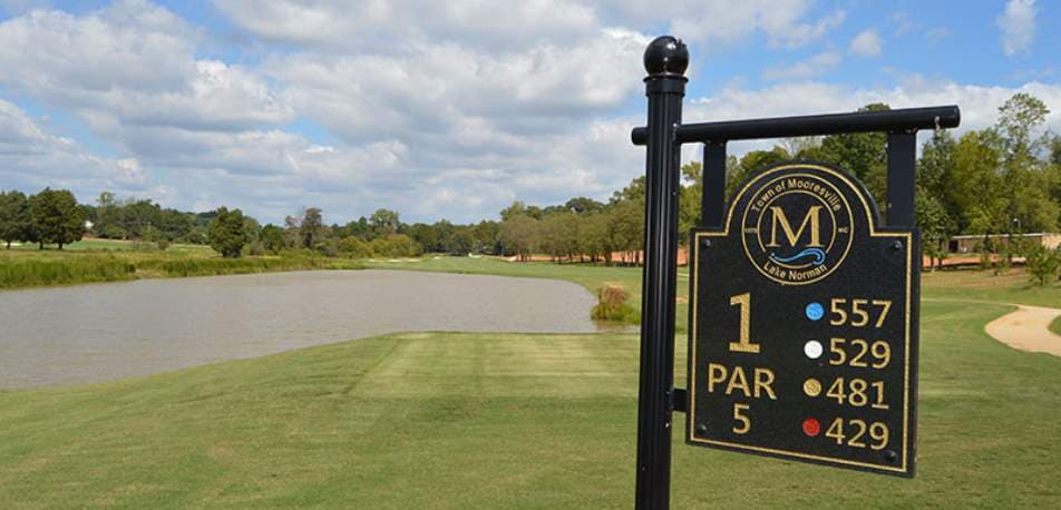 Golf course hole sign with lake and fairway