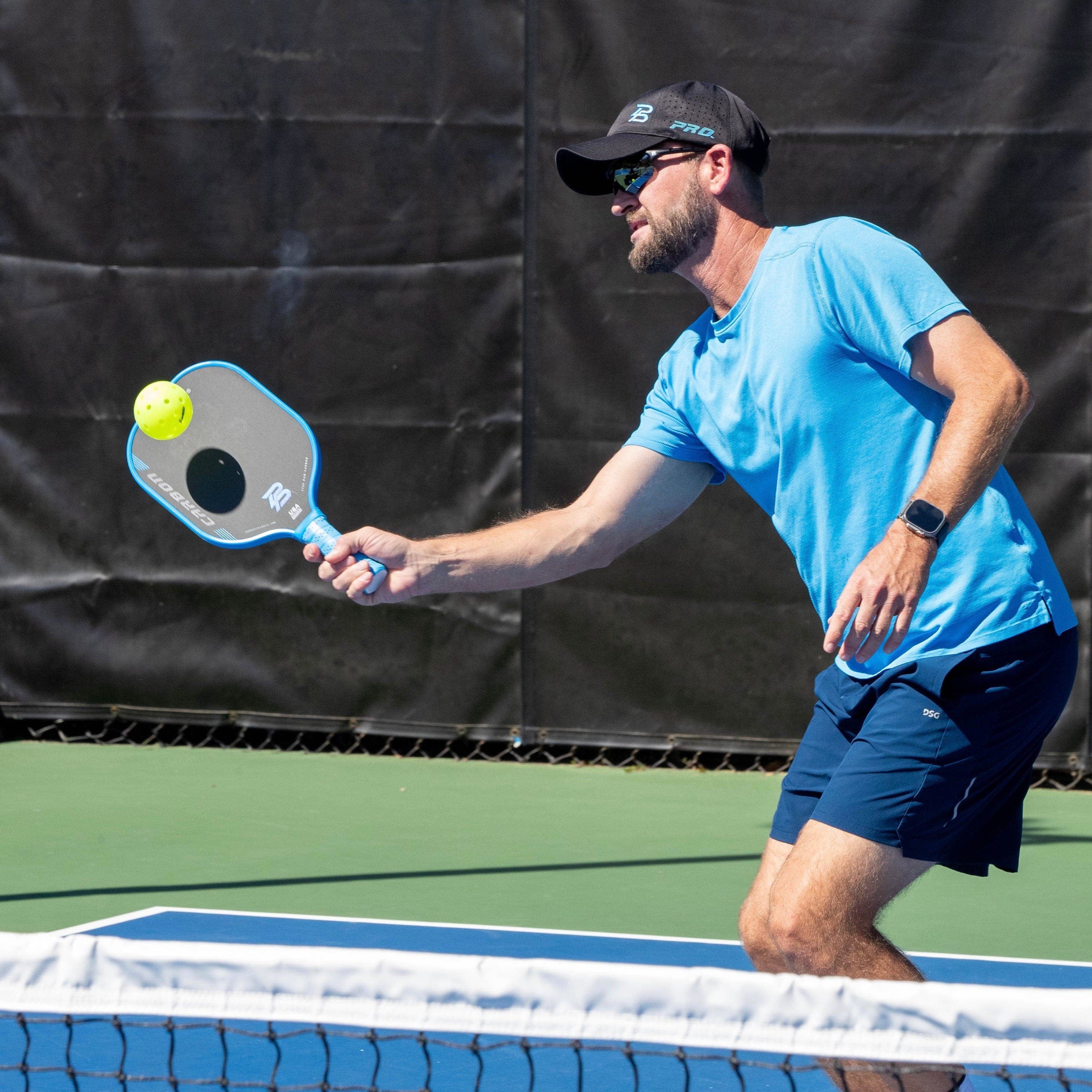 Man hitting pickleball with paddle at net