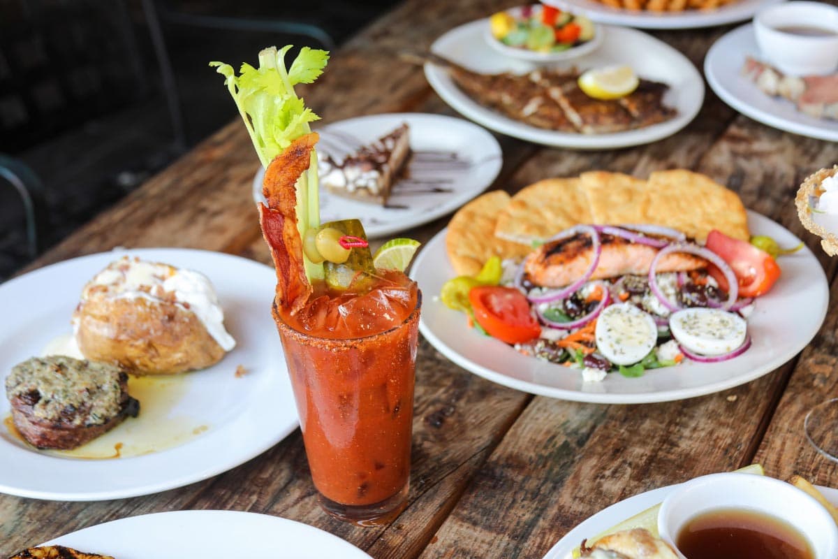 Table full of dishes and a Bloody Mary cocktail