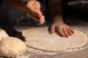 Hands preparing dough on floured surface