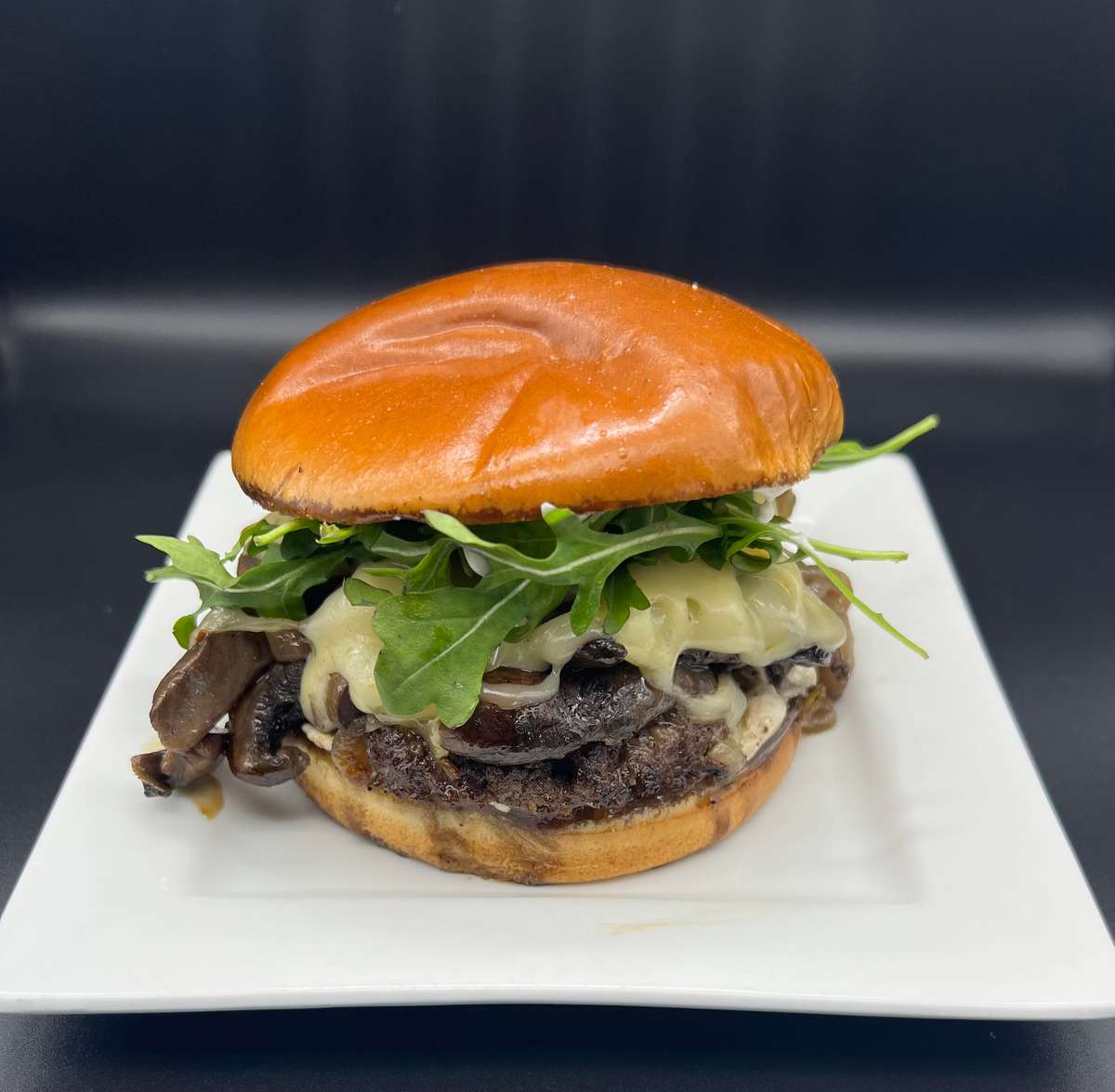 Burger with mushrooms, cheese, and arugula on a plate