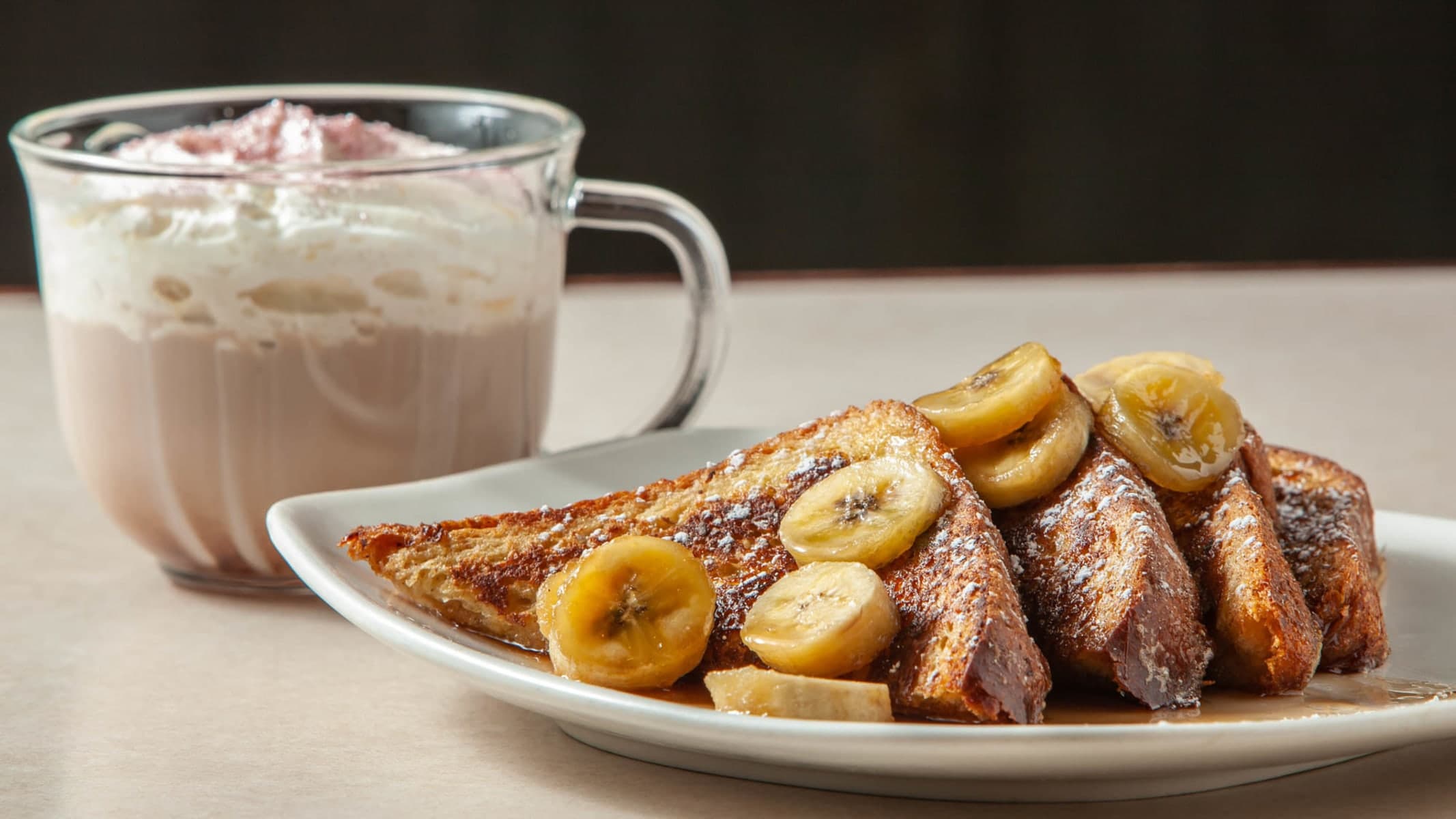 French toast with bananas and drink on plate