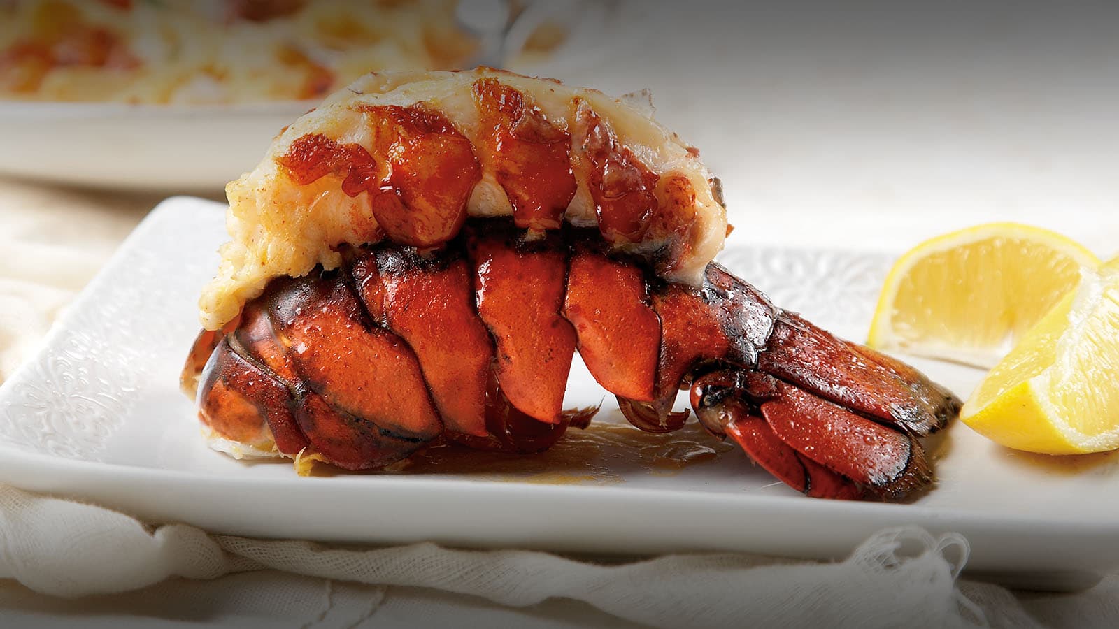 Grilled lobster tail with lemon wedges on plate