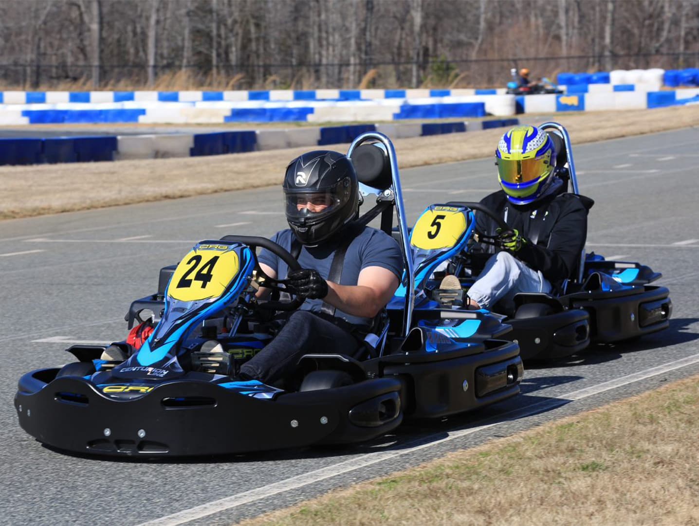 Three go-karts racing on track with drivers