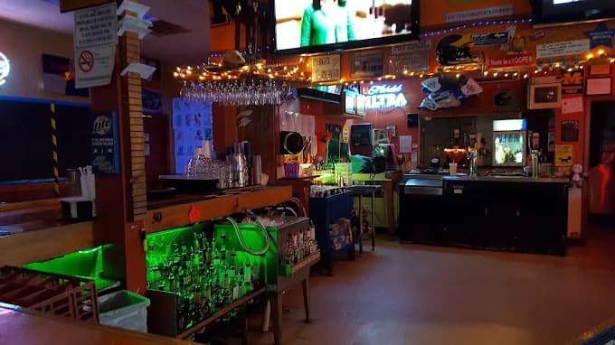 Bar interior with liquor bottles, lights, and TV screens