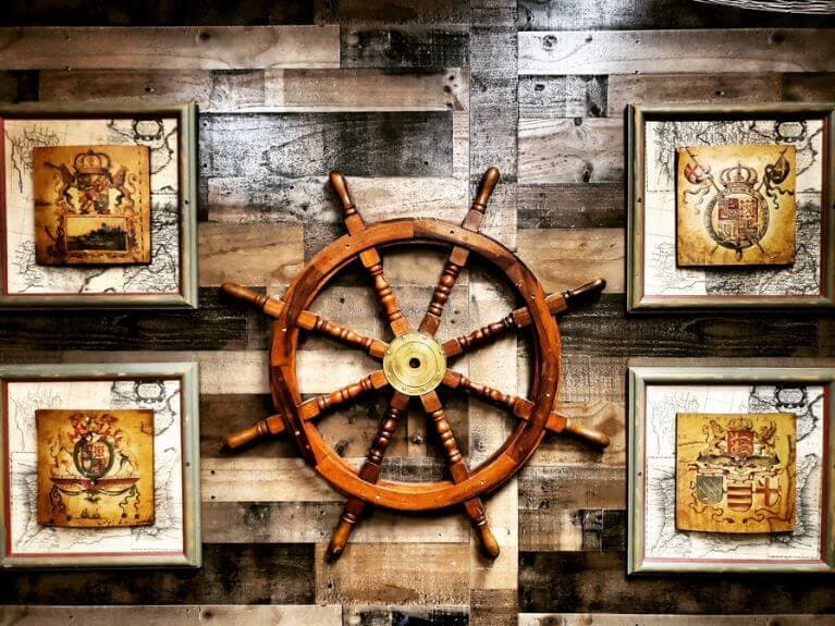 Ship wheel and framed crests on wood wall