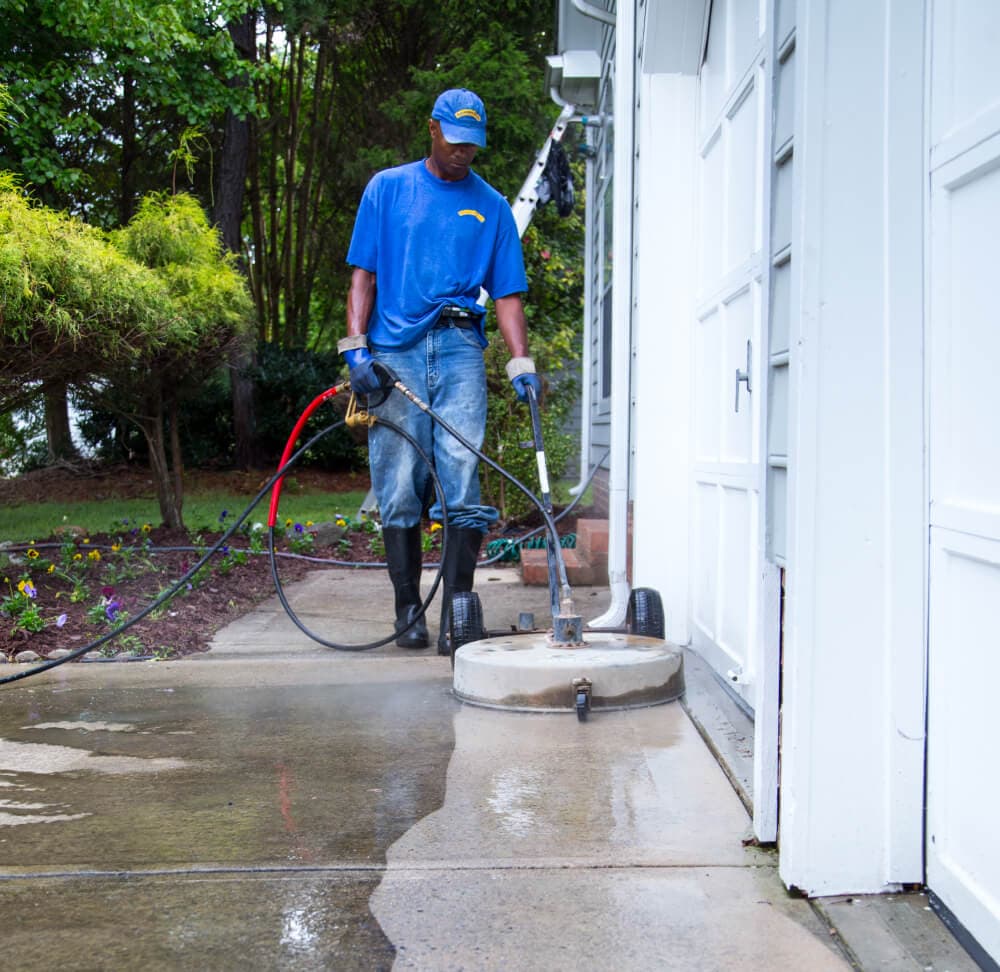 Worker pressure washing concrete patio
