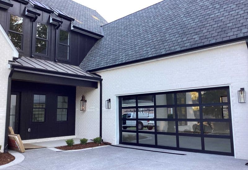 Black framed glass garage door on white house