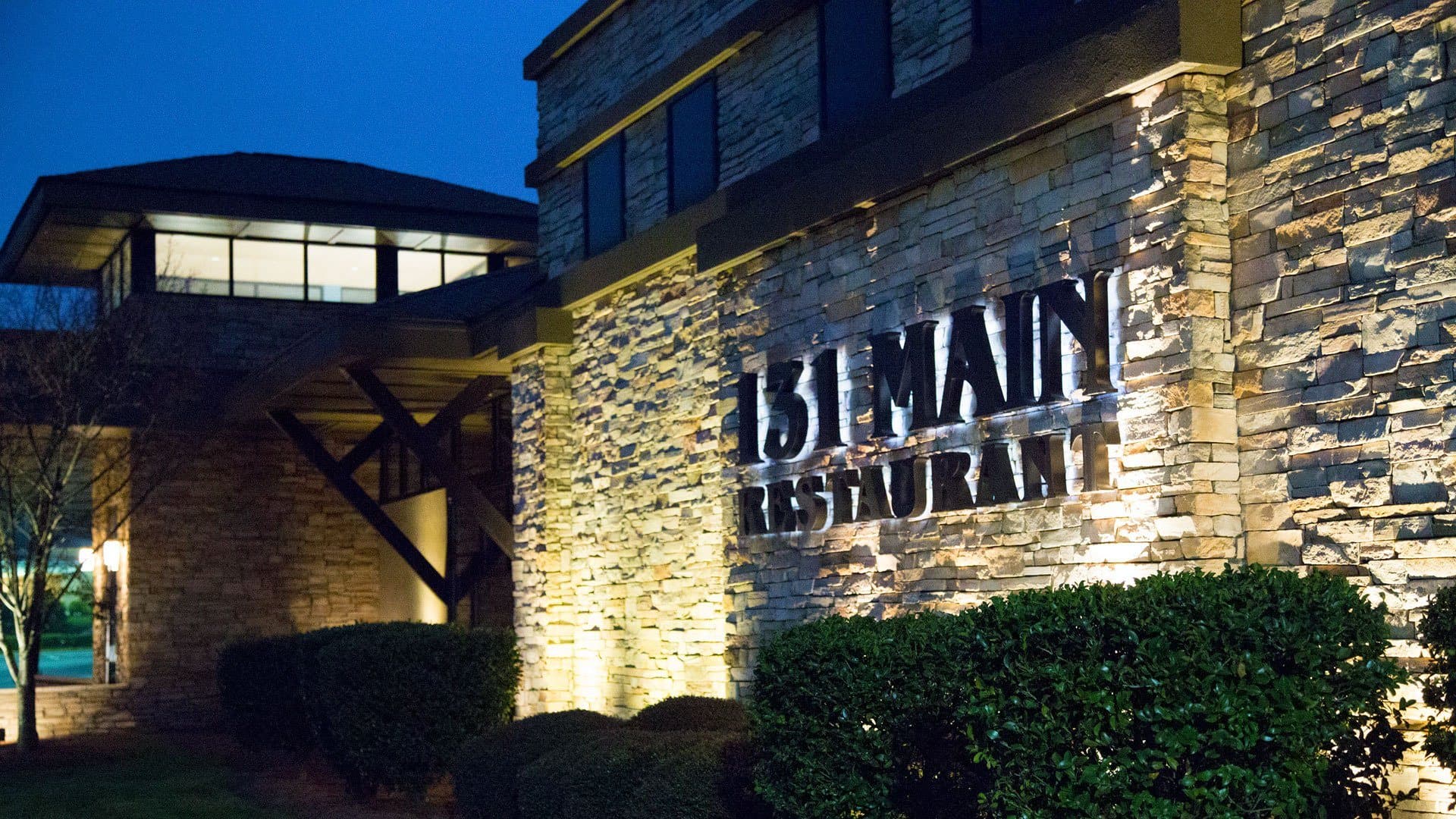 Exterior storefront with illuminated signage at dusk