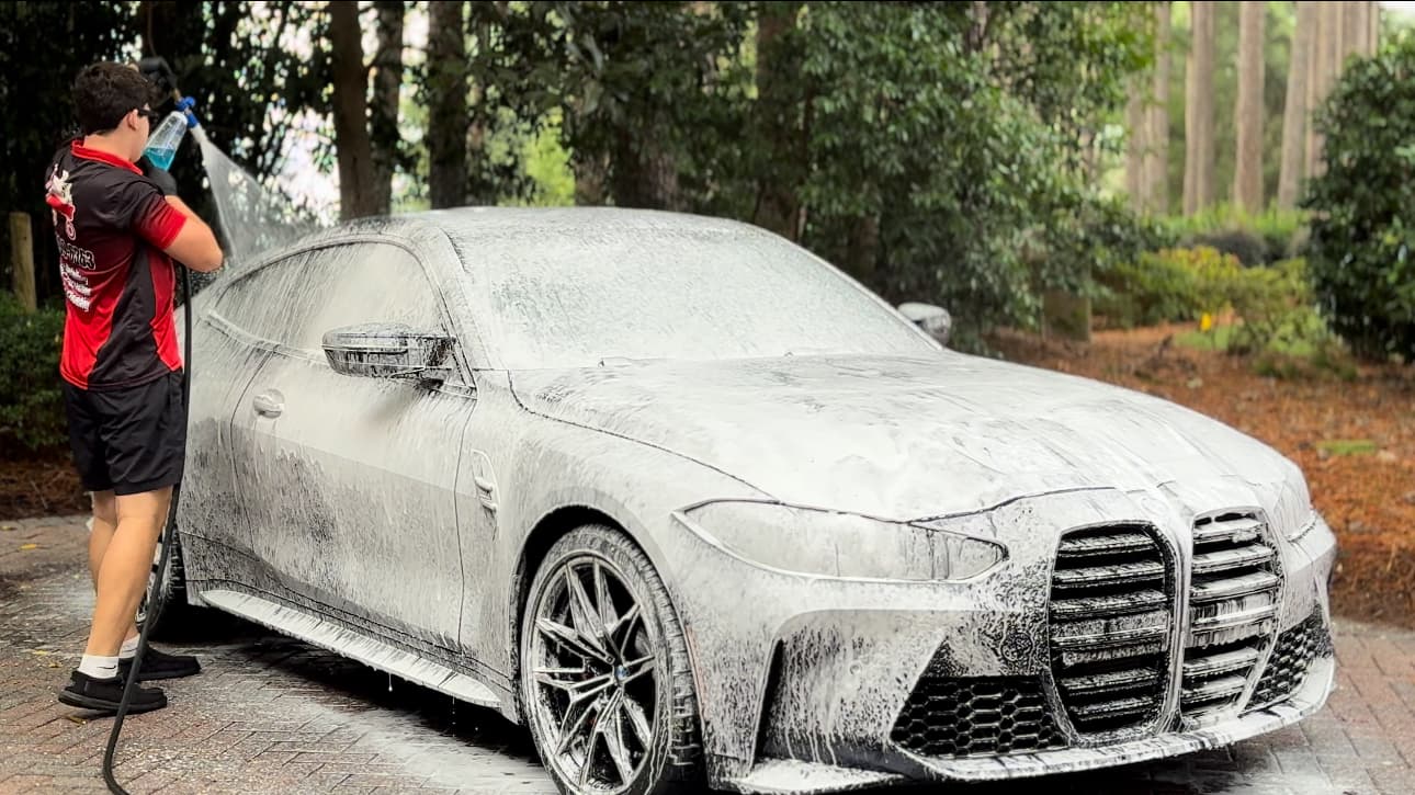 Person washing car with pressure washer