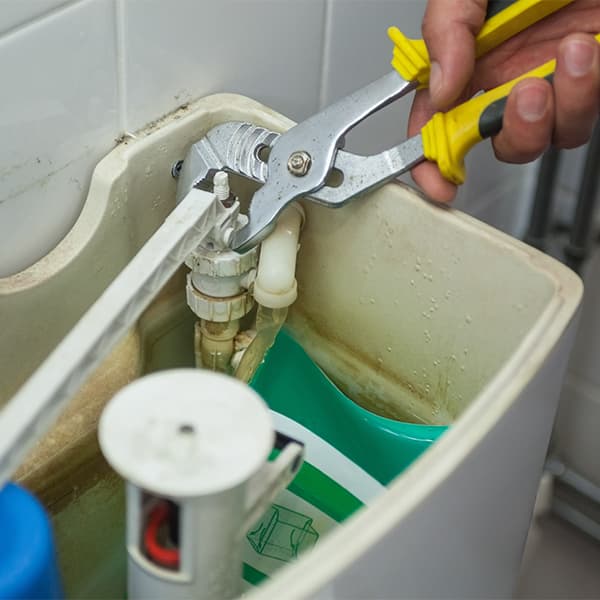HVAC technician repairing toilet fill valve