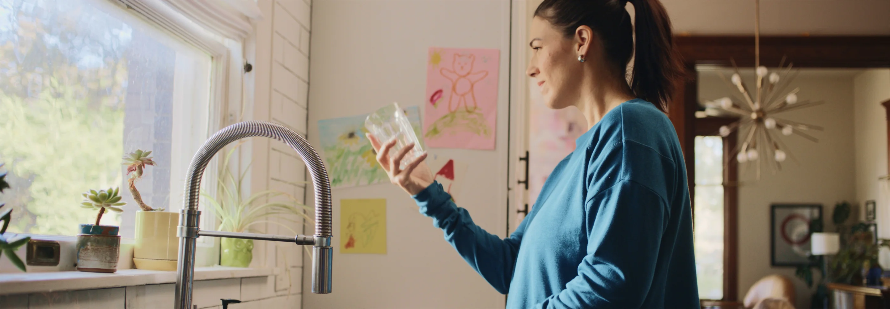 Woman using filtered water at kitchen sink