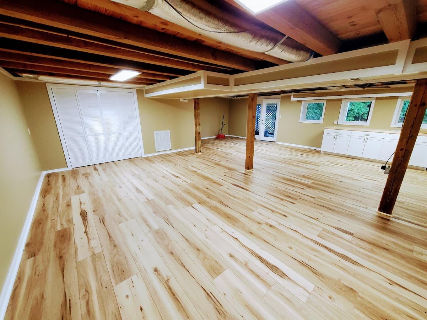 Finished basement with hardwood flooring and beams