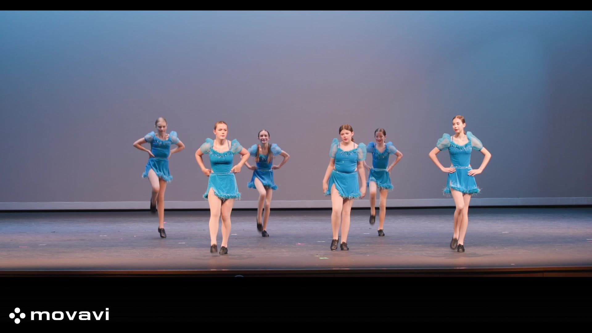 Young dancers performing on stage in blue costumes