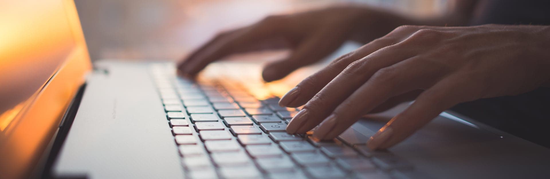 Hands typing on laptop keyboard