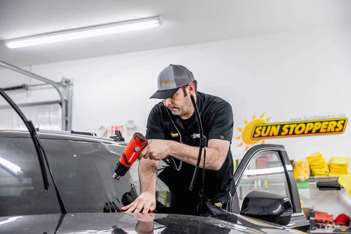 Technician applying window tint to vehicle