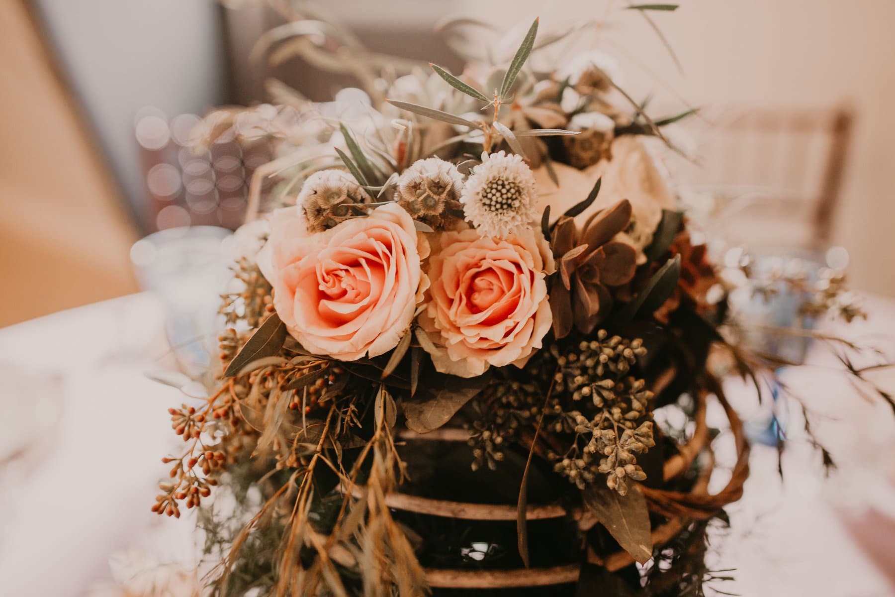 Floral arrangement with coral roses and dried botanicals