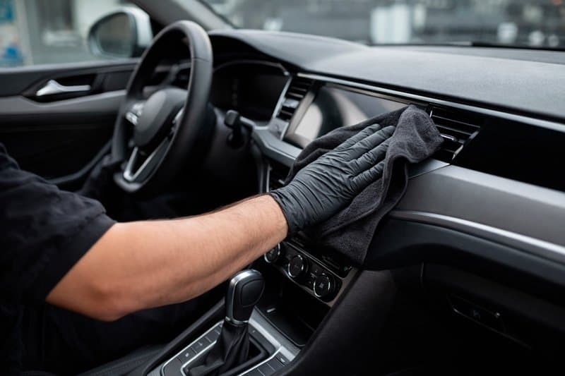 Worker cleaning car interior with microfiber cloth