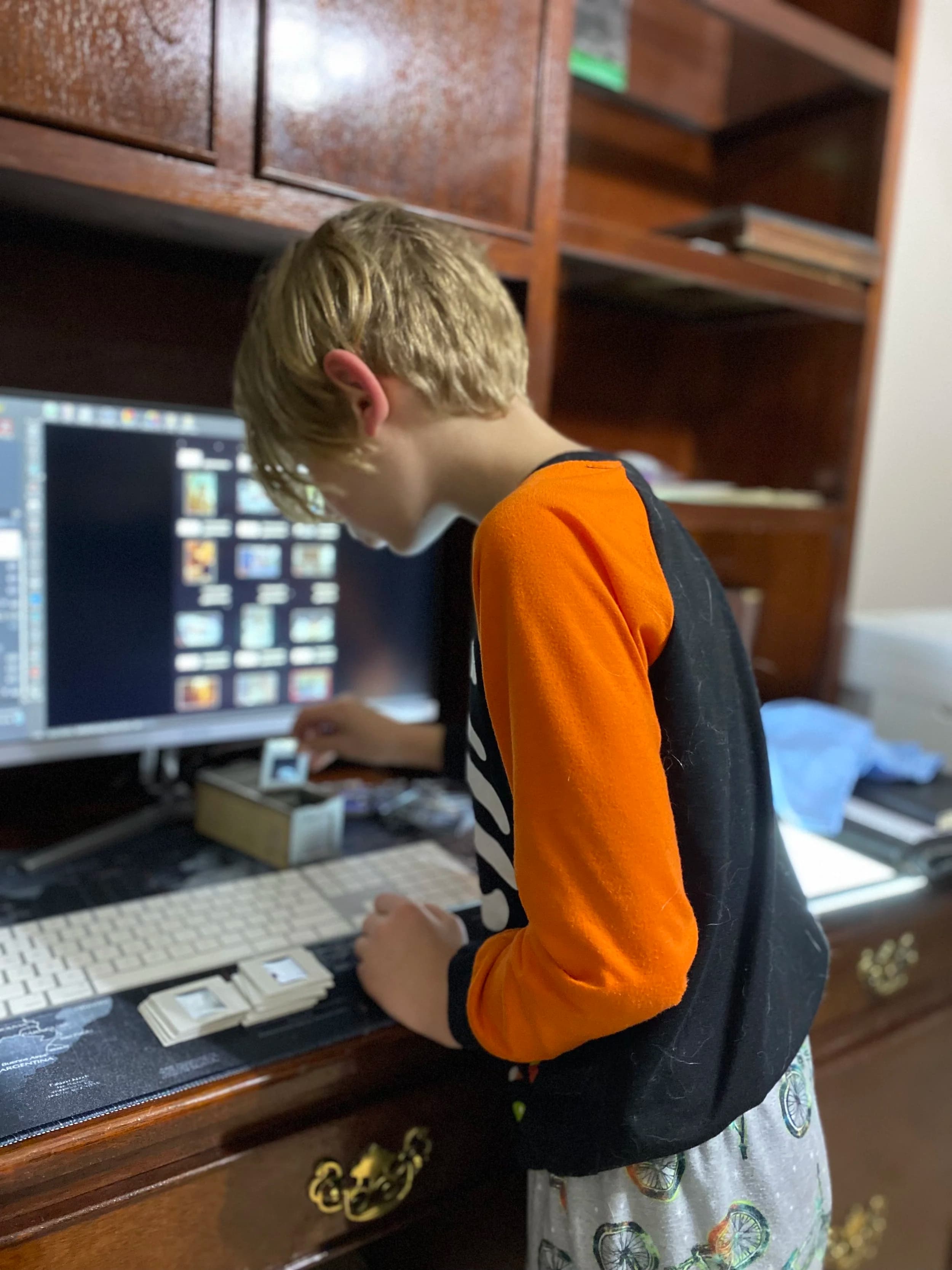 Child working at computer workstation, digitizing photos