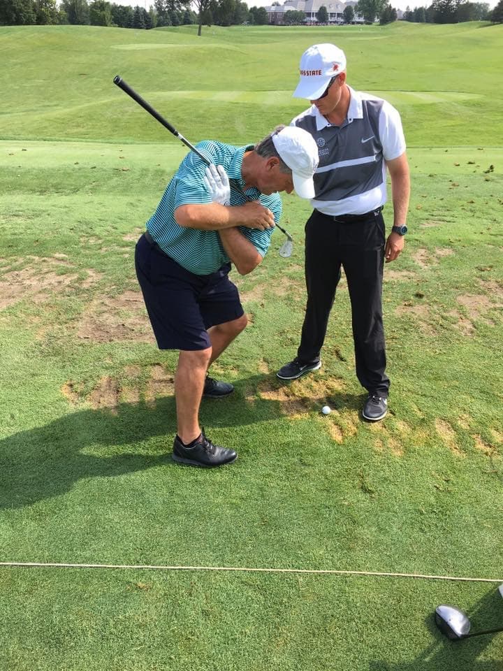 Golf instructor teaching student swing technique